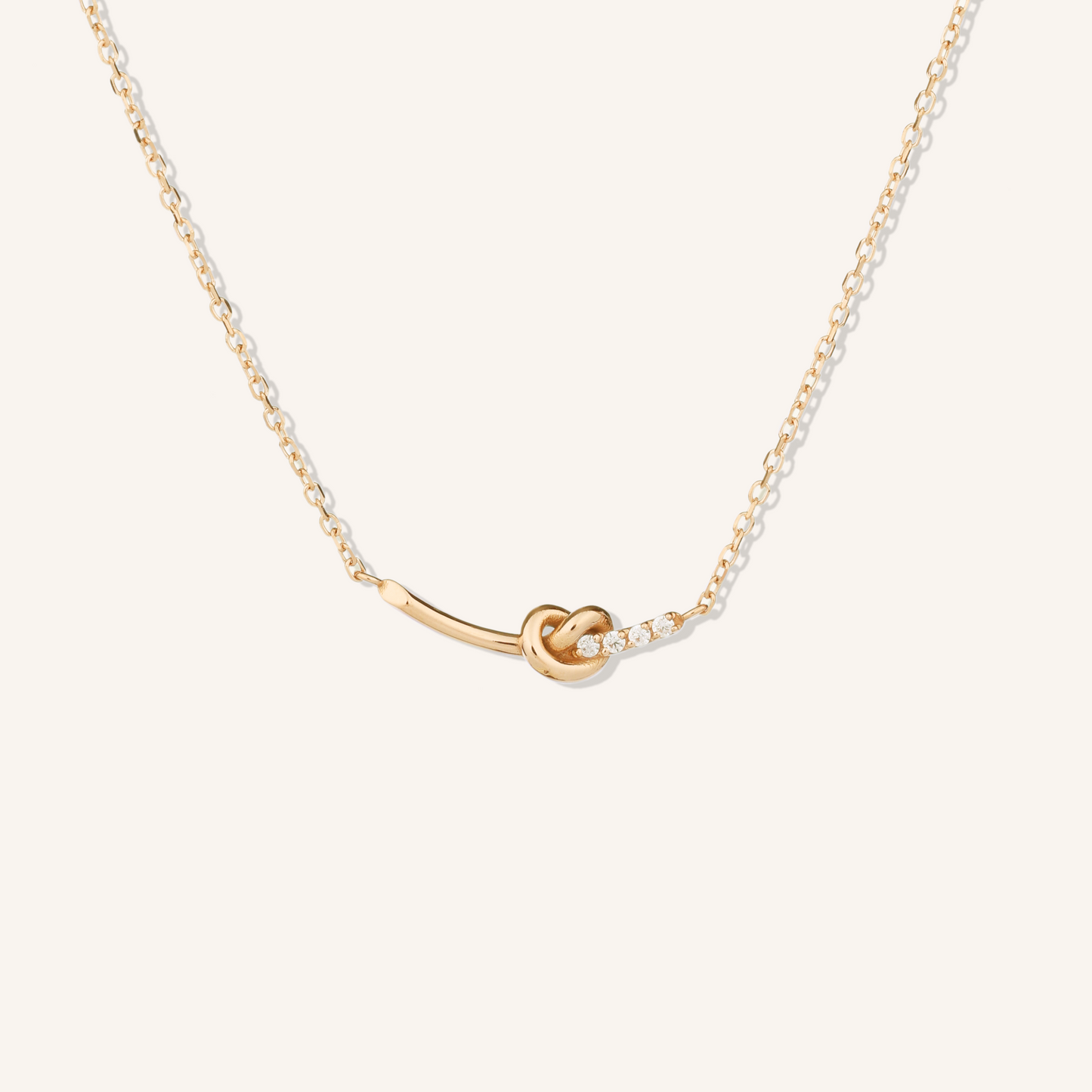 Gold necklace with a knot pendant on a white background