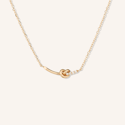 Gold necklace with a knot pendant on a white background