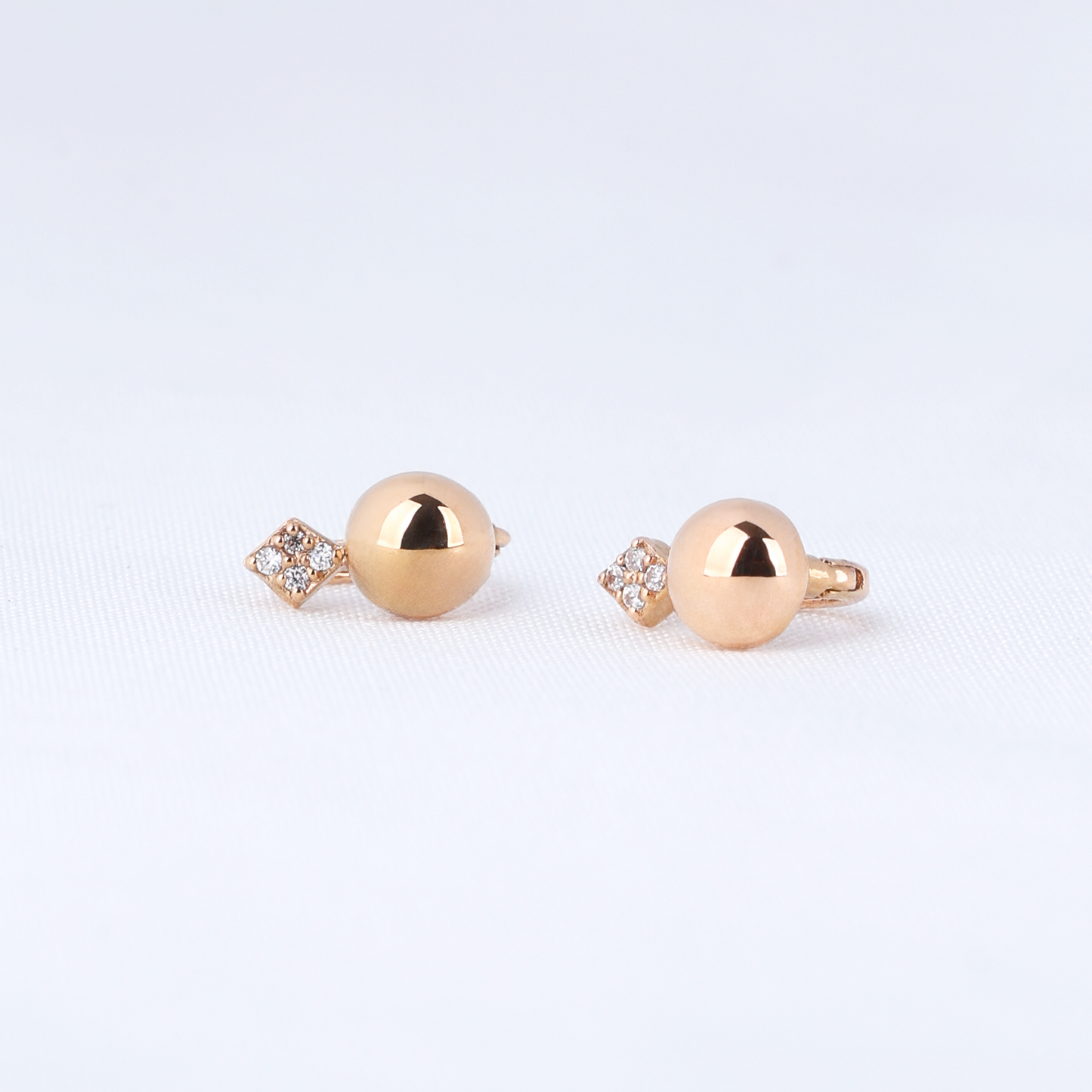 Pair of gold ball earrings on a light gray background