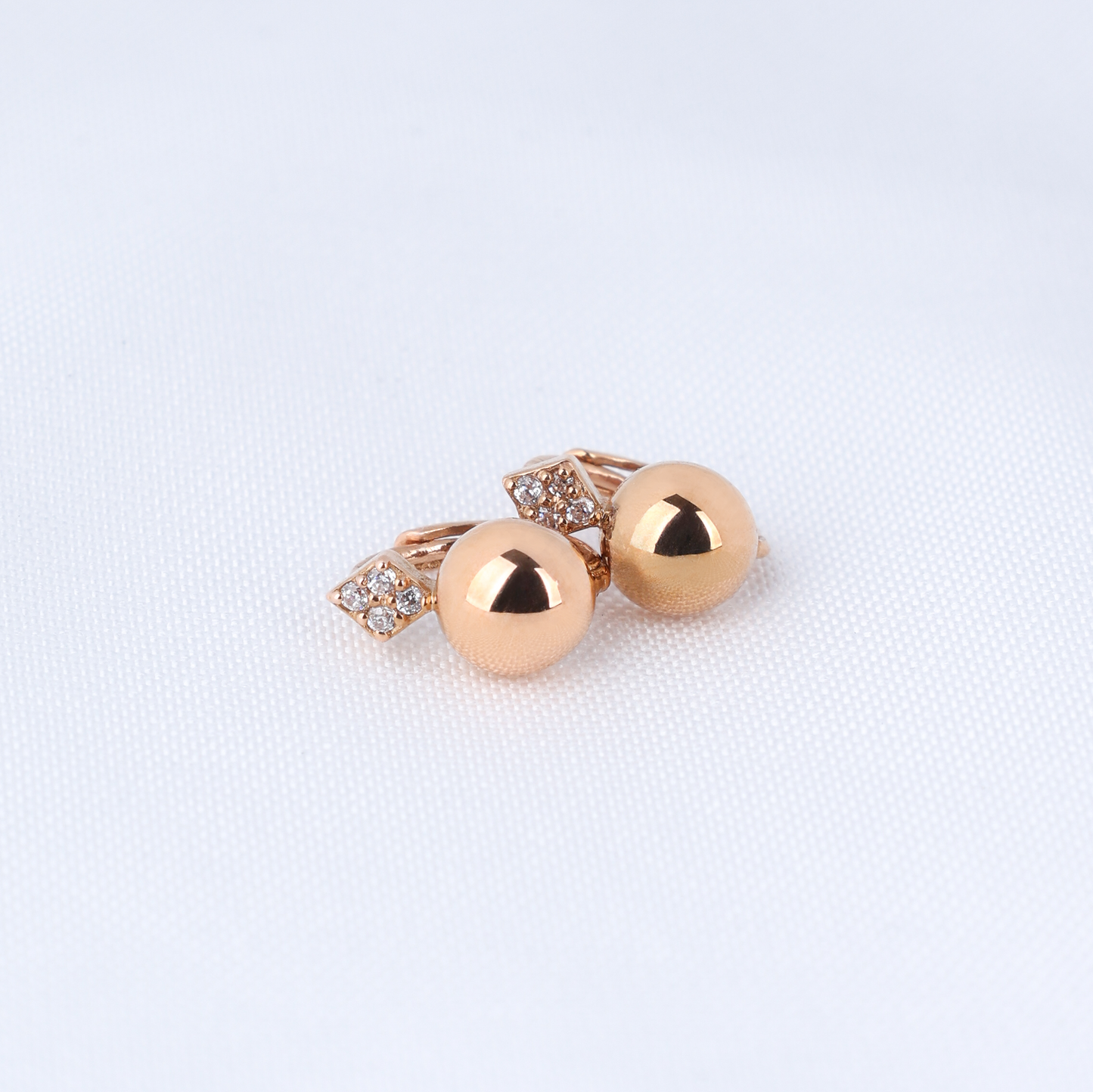 Pair of gold earrings on a light fabric background