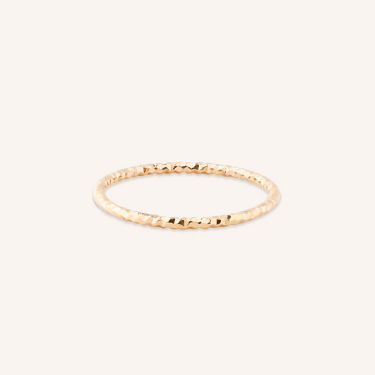 Gold ring with a textured band on a white background